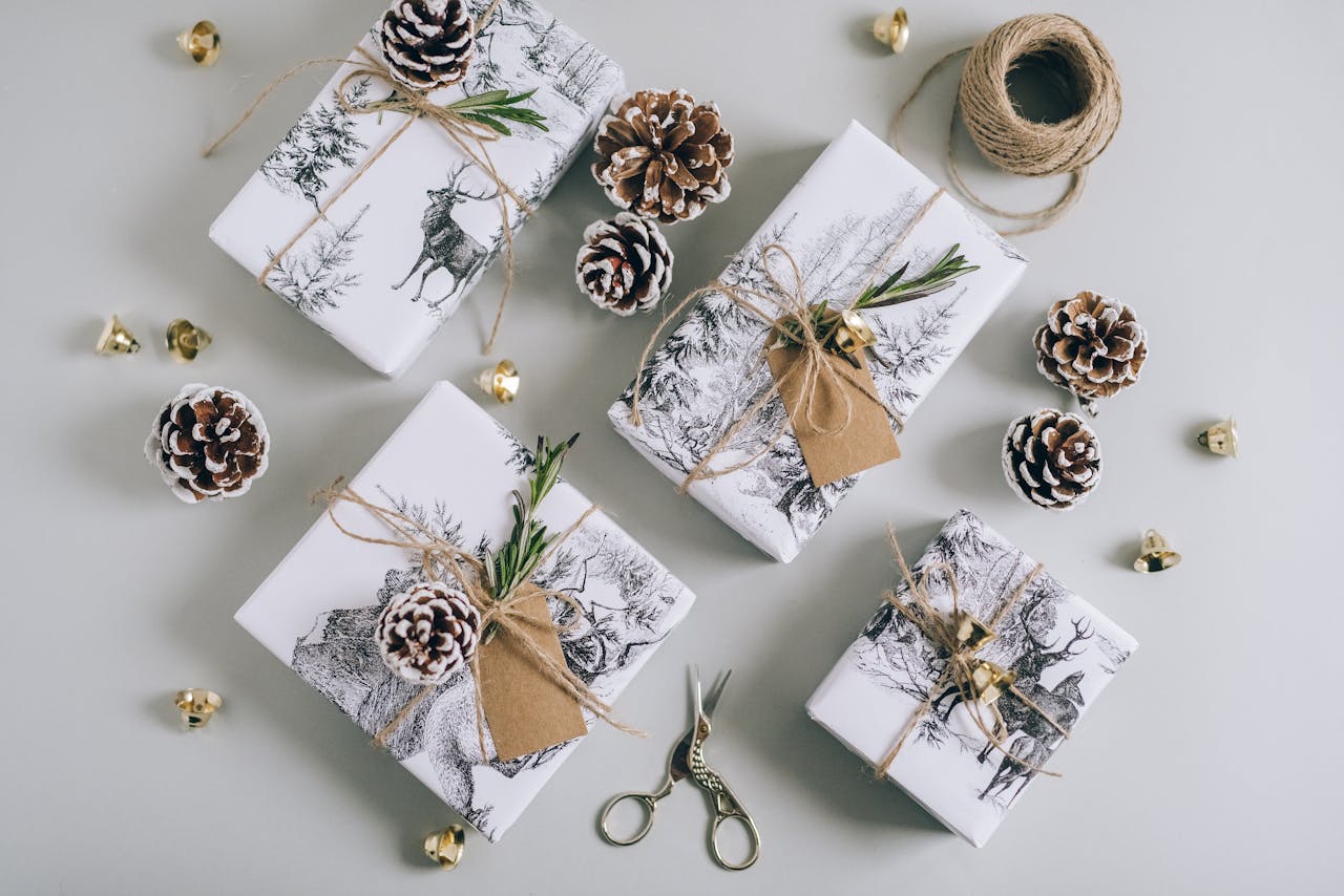 Stylish Christmas gifts wrapped in deer-themed paper, adorned with pine cones and hemp twine for a rustic touch.